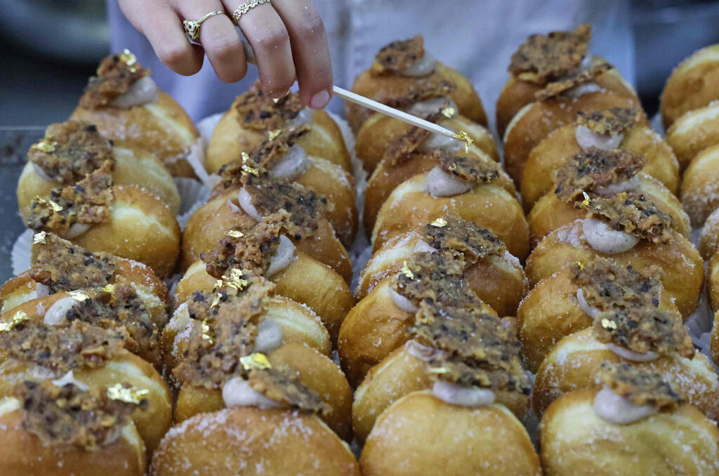 'Abu Dhabi' doughnut (Photo: AFP) A gold leaf is added atop a date-flavoured "Abu Dhabi" doughnut created for the Jewish holiday of Hanukkah and in honour to the new diplomatic relations between Israel and the United Arab Emirates, at Kadosh pastry shop in Jerusalem
