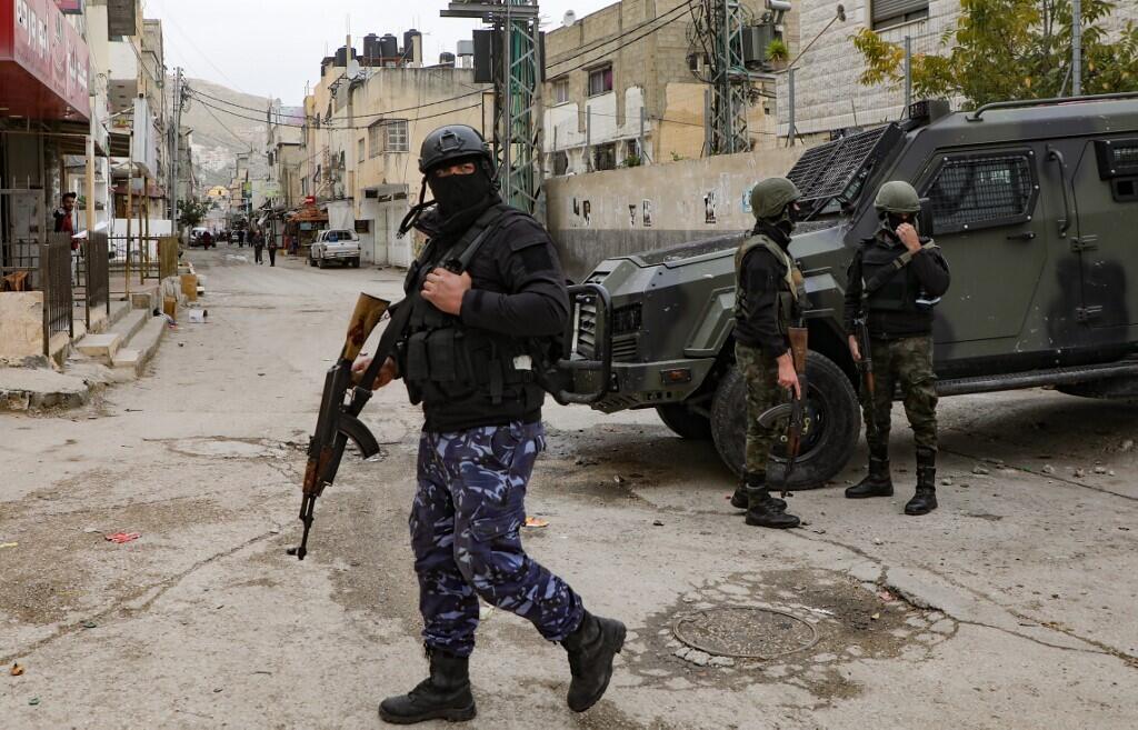Palestinian Authority security forces in balaclavas stand by an armored vehicle at the entrance to Balata camp, near the West Bank city of Nablus 