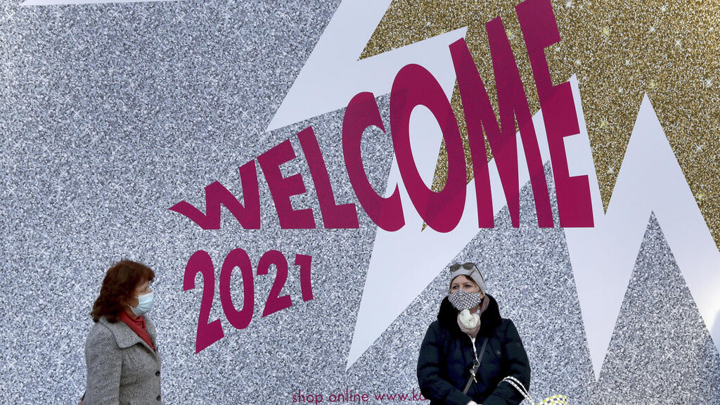 People in front of a wall painting welcoming the new year in Berlin, Germany (Photo: AP) People wear face masks as they queue in front of the 'KaDeWe' department store in Berlin, Germany,