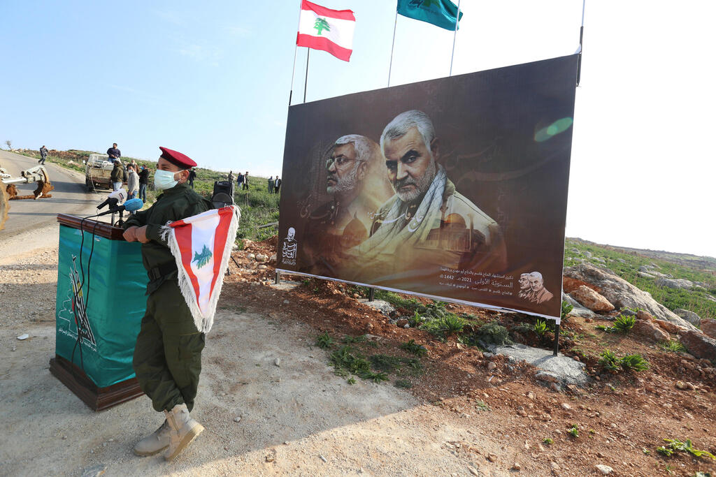 צילום: רויטרס פעיל חיזבאללה ליד תמונת קאסם סולימאני ואבו מהדי אל מוהנדס טקם בכפר ב לבנון
