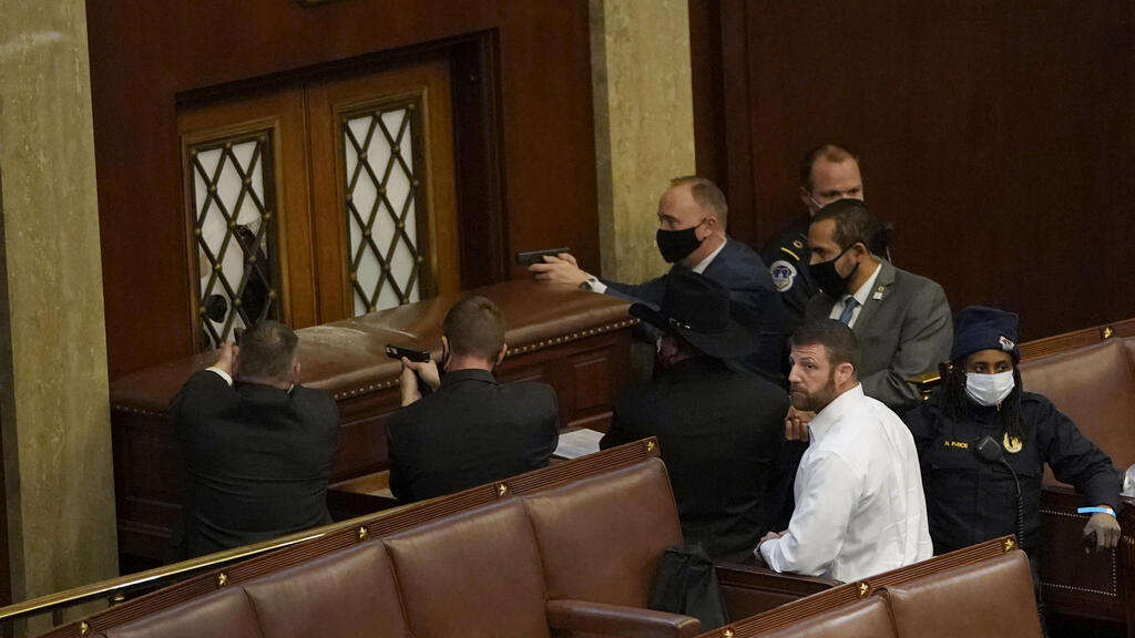 U.S. Capitol police officers point their guns at a door to the Senate Chamber as a mob tries to break in, Jan, 6, 2021 (Photo: TNS) U.S. Capitol police officers point their guns at a door that was vandalized in the House Chamber during a joint session of Congress
