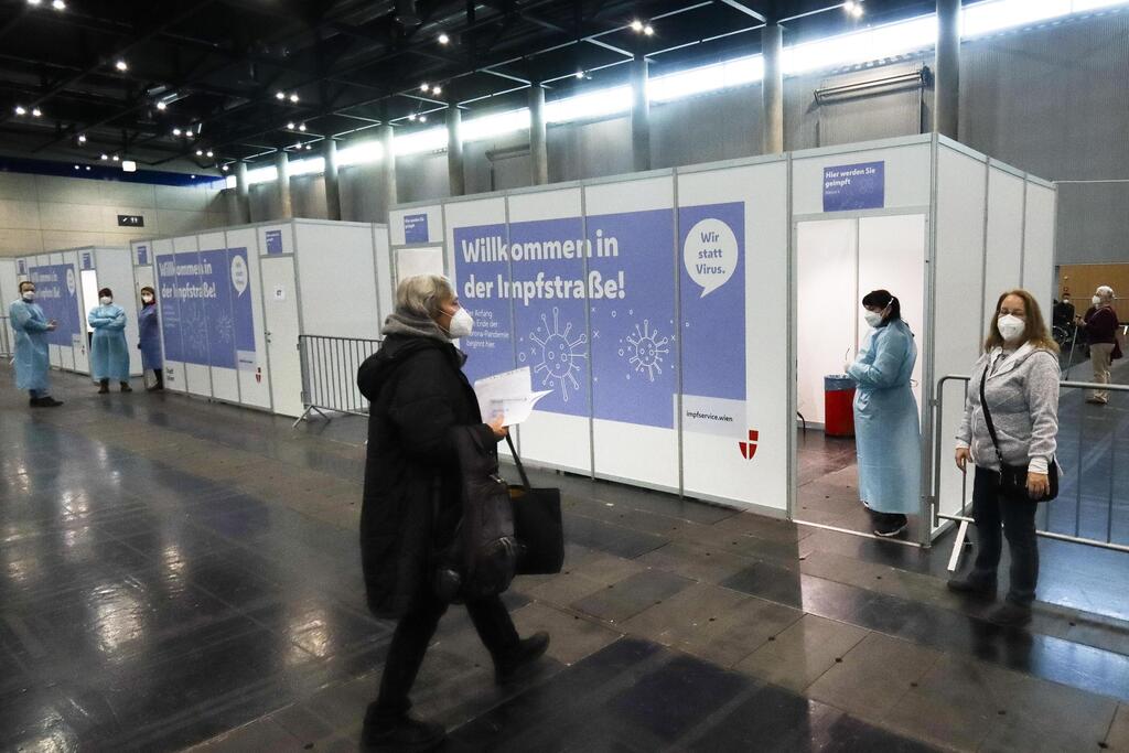 A Holocaust survivor, left, arrives to get a shot of the COVID-19 vaccine at a vaccination center on International Holocaust Remembrance Day in Vienna, Austria