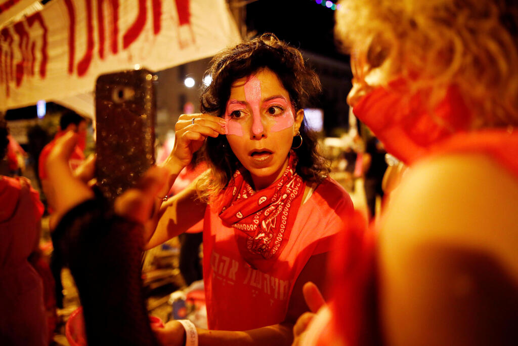 'Pink Front' member Yarden Grosser applies face paint as she takes part in a weekly anti-Netanyahu demonstration in Jerusalem last OCtober 