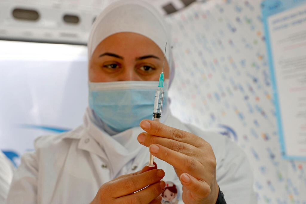 A nurse prepares a vaccine dose at a pop-up clinic in Jaffa (Photo: AFP) עמדת חיסונים ניידת של מכבי ביפו