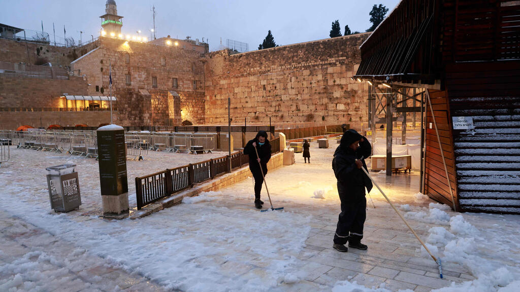 מנקים את שאריות השלג באזור הכותל המערבי (צילום: AFP) מזג אוויר שלג הכותל המערבי ירושלים