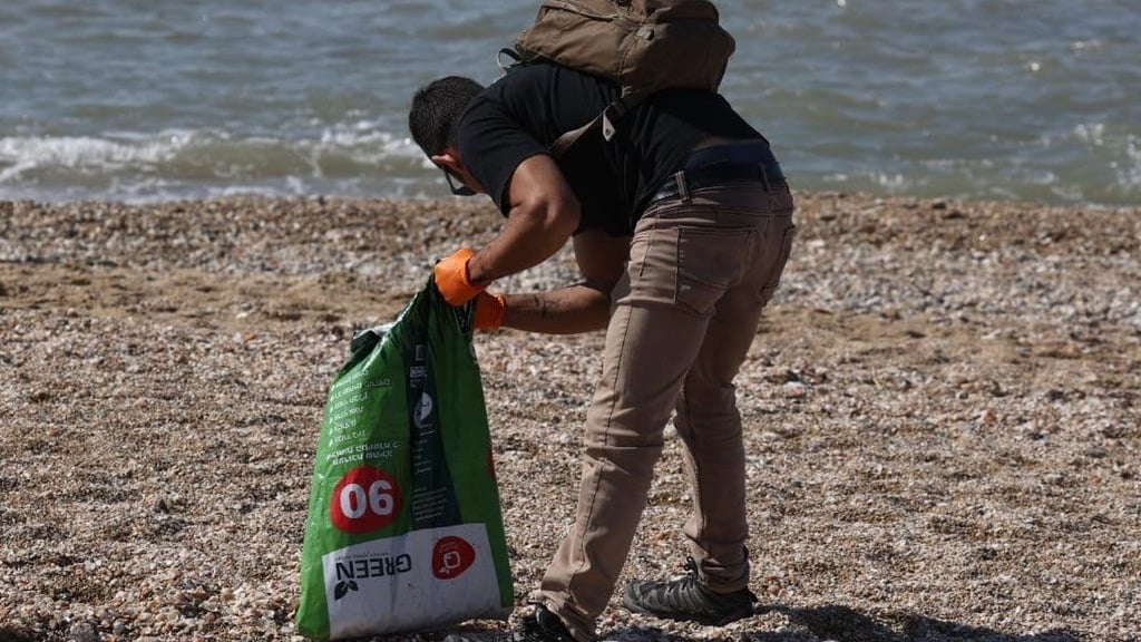 A volunteer collects remnants of tar from the Tel Aviv beach after an oil spill caused an ecological disaster earlier this month (Photo: Moti Kimchi) ניקיון הזפת שנסחפה לחופי תל אביב