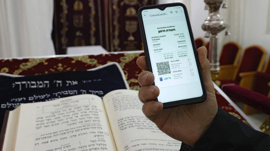 Digital Green Pass being shown on the phone in synagogue (Photo: AFP) מתפללים בבתי הכנסת עם התו הירוק