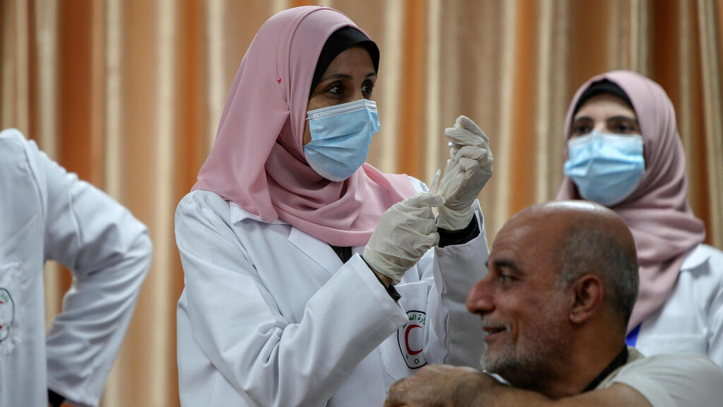: A health worker prepares to vaccinate former Palestinian health minister Jawad Tibi against the coronavirus disease