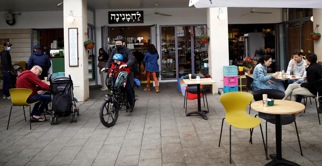 Guests sit and take away food and drinks from a Tel Aviv cafe as Israel further the eases coronavirus restrictions, March 7, 2021 