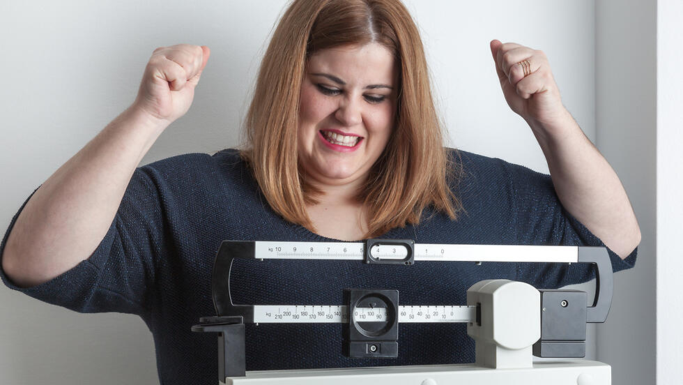 אשה שמנה מאושרת על המשקל