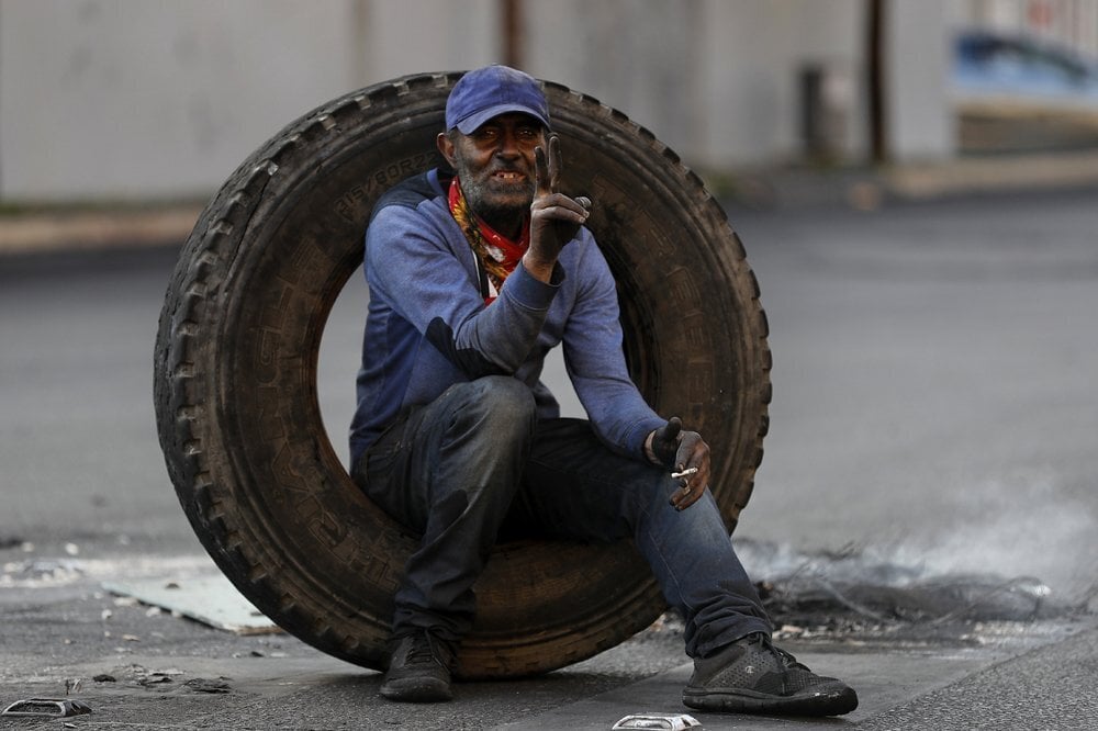 a protester flashes a victory sign as he aims to block a road during a protest, in Beirut, Lebanon 