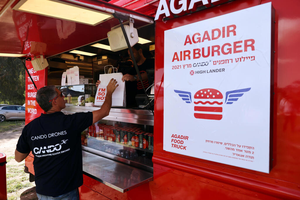A man picks up a take away food delivery as he takes part in a demonstration whereby delivery drones from various companies flew in a joint airspace and were managed by an autonomous control system in Haifa, near Hadera 