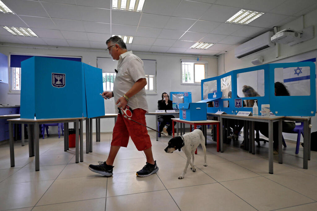 An Israeli man leads his dog as he casts his ballot at a polling station in Tel Aviv on March 23, 2021 