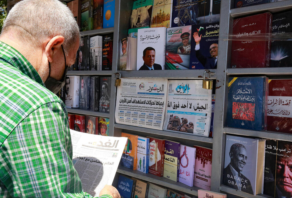 Man standing at a newspaper stand and reading about a wave of arrests following an alleged coup attempt in the Jordanian capital of Amman 
