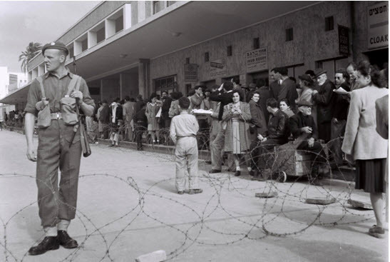 A British soldier guarding the fenced off Tel Aviv central bus station during a curfew imposed under martial law in 1947 