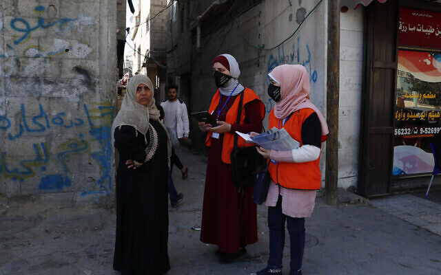 Members of the Central Elections Commission’s field team checks to register a local woman to the electoral roll, at the main road of Gaza City 