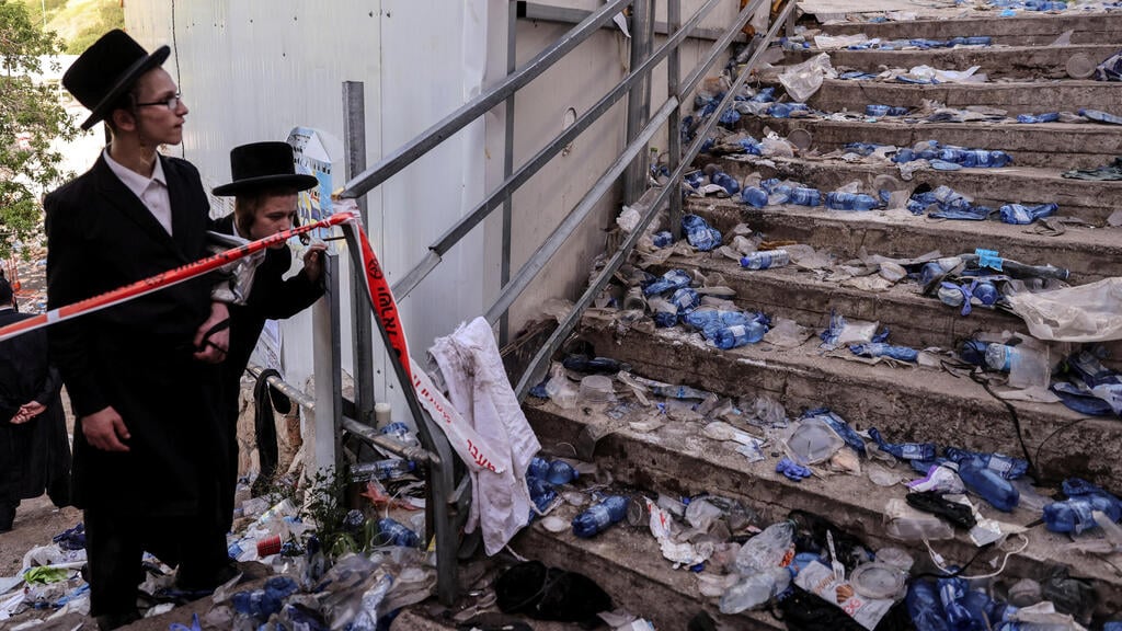 Two teens look on at the aftermath of the Meron disaster (Photo: Reuters) מקום הנפילה בו קרה האסון בהר מירון
