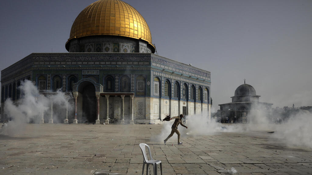 A Palestinian runs away from tear gas during clashes with Israeli security forces in front of the Dome of the Rock Mosque at the al-Aqsa Mosque compound on Monday 