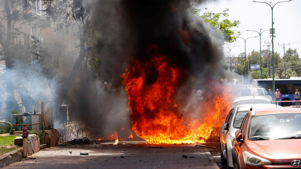 A car in Ashkelon burns after it was hit by a Gaza rocket (Photo: AFP) פגיעת רקטות במכוניות באשקלון