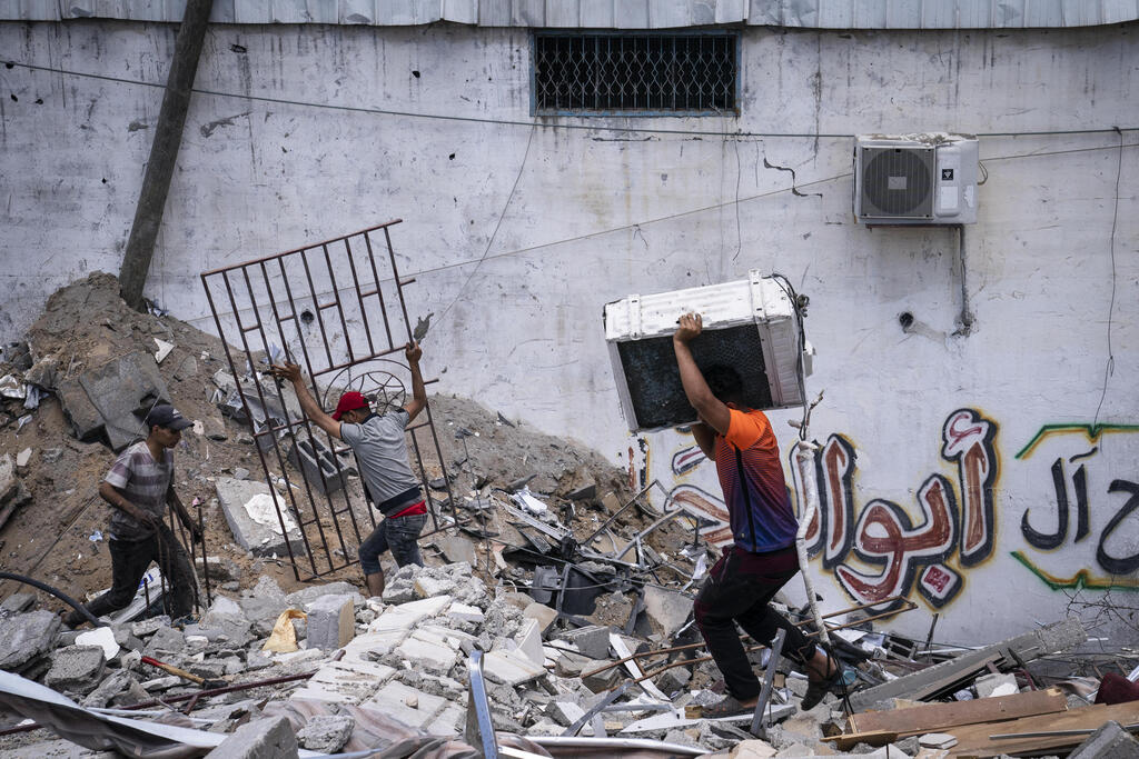 Children trying to salvage goods from underneath the wreckage following an Israeli strike in the Gaza Strip (Photo: AP) ההרס בעזה