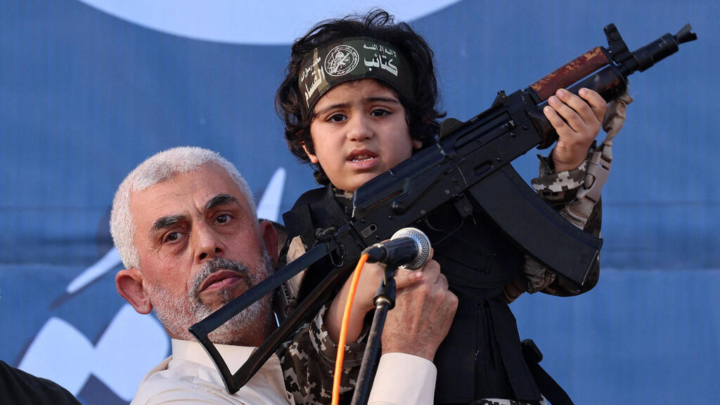 Hamas leader Yahya Sinwar holds the child of an Al-Qassam Brigades fighter, who was killed in the recent fighting with Israel 