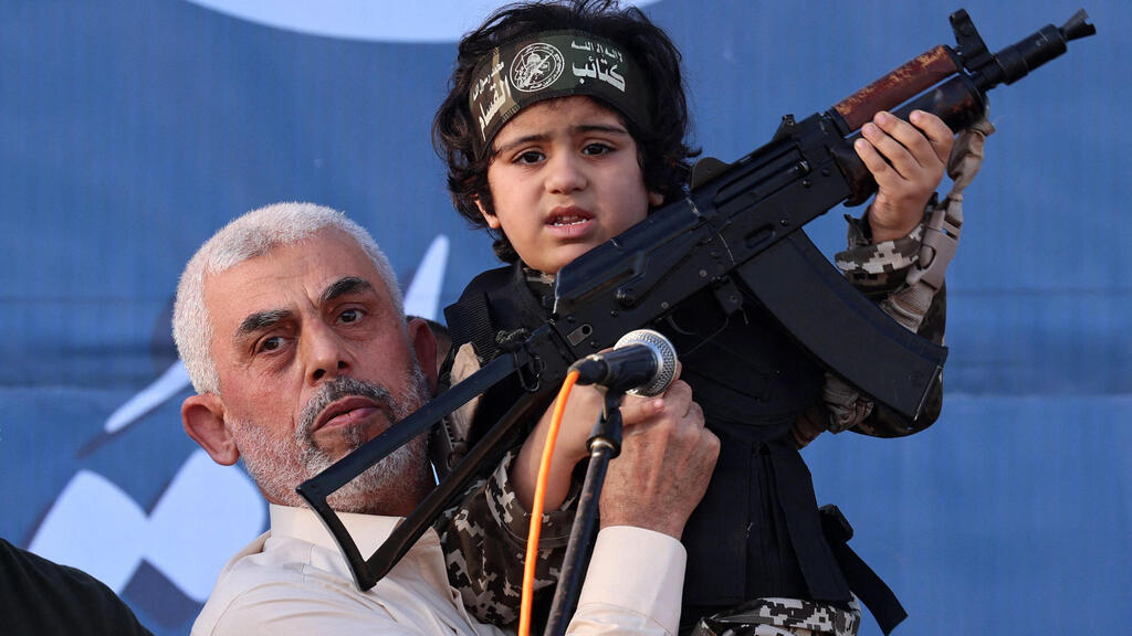 Hamas leader Yahya Sinwar holds the child of an Al-Qassam Brigades fighter, who was killed in the recent fighting with Israel 