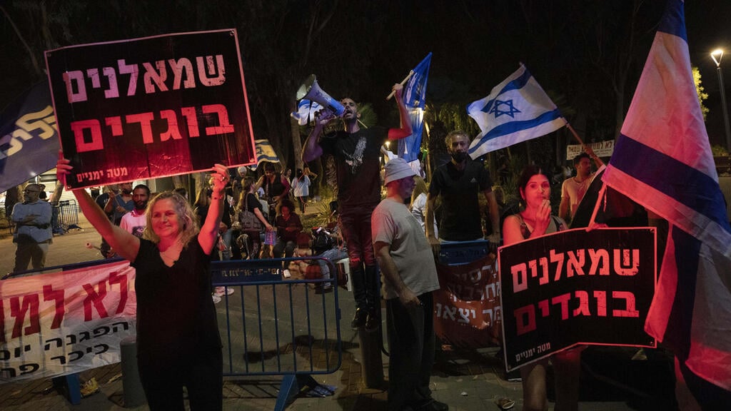 Pro Netanyahu protesters outside the home of Ayelet Shaked hold up signs calling Yamina party members 'traitors' (Photo:: AP) הפגנה של תומכי ימין ושמאל מול ביתה של איילת שקד