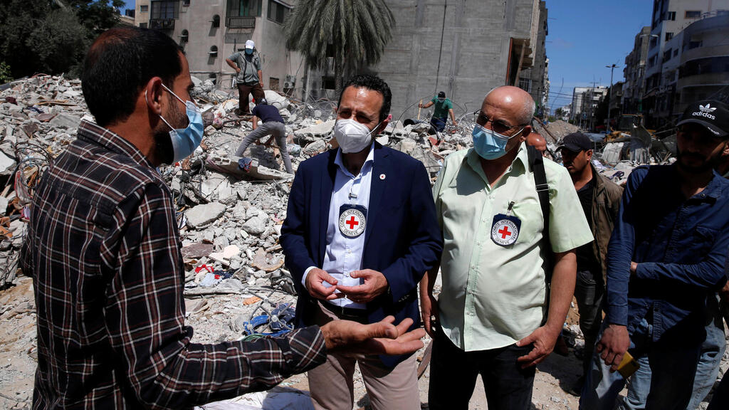 Robert Mardini gestures as he speaks with a Palestinian man near the rubble of a house destroyed in Israeli air strikes during Israeli-Palestinian fighting, in Gaza City 