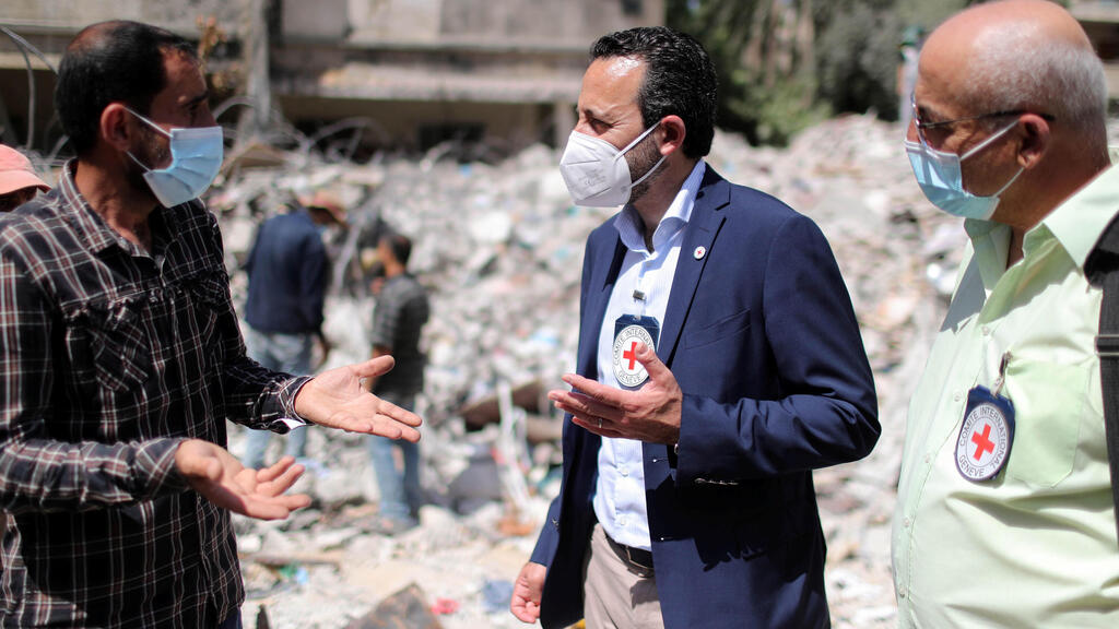 Robert Mardini gestures as he speaks with a Palestinian man near the rubble of a house destroyed in Israeli air strikes during Israeli-Palestinian fighting, in Gaza City 