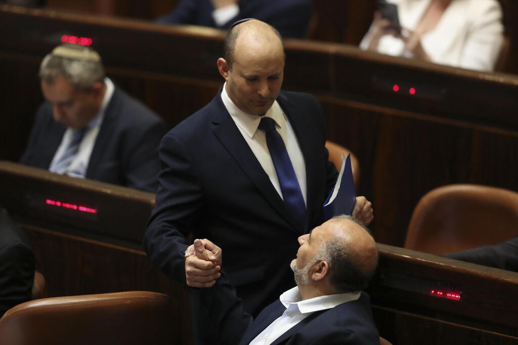 Mansour Abbas clasps hands with Prime Minister Naftali Bennett during the Knesset session to approve their new coalition government, June 13, 2021 (Photo: AP) השבעת הממשלה