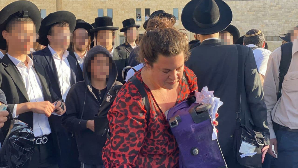 Tammy Gottlieb collects the pages torn out of prayer books by Haredi men following a confrontation last Friday at the Western Wall (Photo: Irina Lutt) תמי גוטליב אוספת את דפי הסידורים הקרועים