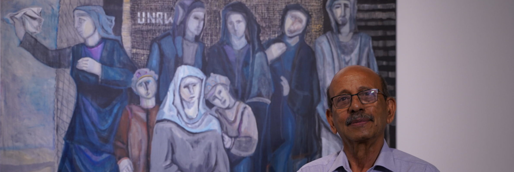 Palestinian artist Abed Abdi stands in front of his painting 'Refugees Waiting for Their Return' (2018) at the Haifa Museum of Art