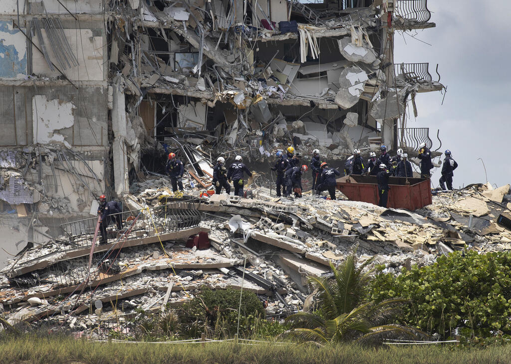 : Members of the South Florida Urban Search and Rescue team look for possible survivors in the partially collapsed 12-story Champlain Towers South condo building on June 26, 2021