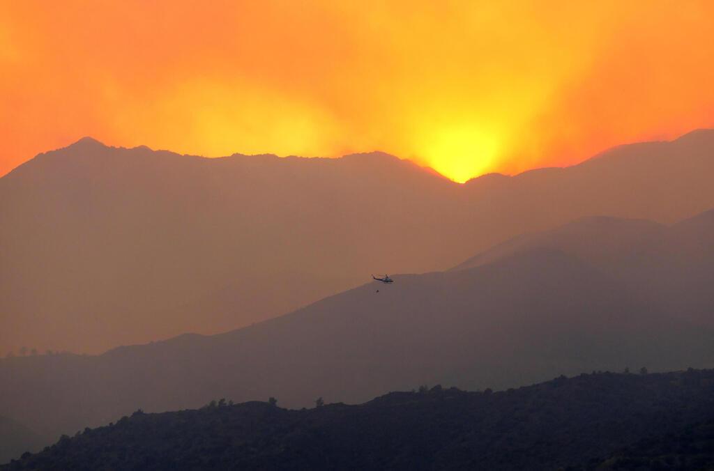 A helicopter flies over a forest fire, in the Larnaca mountain region of Cyprus,  July 3, 2021 