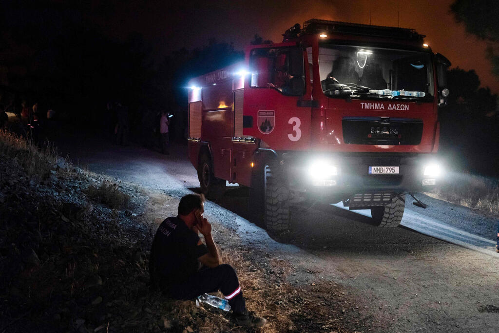 A firefighter uses his mobile phone in village of Vavatsina in the Larnaca district of Cyrus, as efforts continue to control a giant wildfire raging in the mountainous area, July 3, 2021 