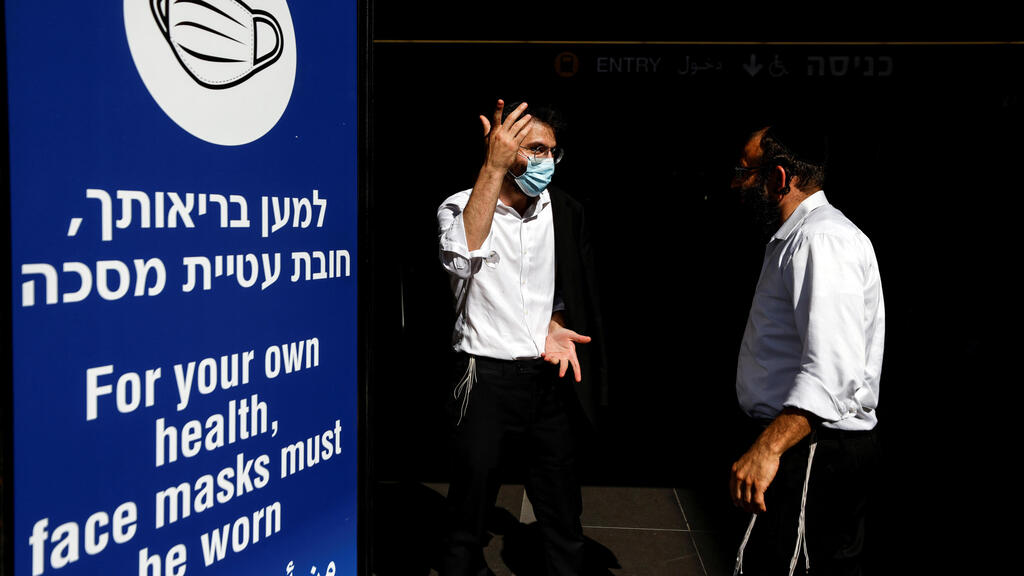 Men stand next to an information banner at Israel's Ben Gurion International Airport, amid a spread of the Delta variant of the coronavirus disease (COVID-19), near Tel Aviv 
