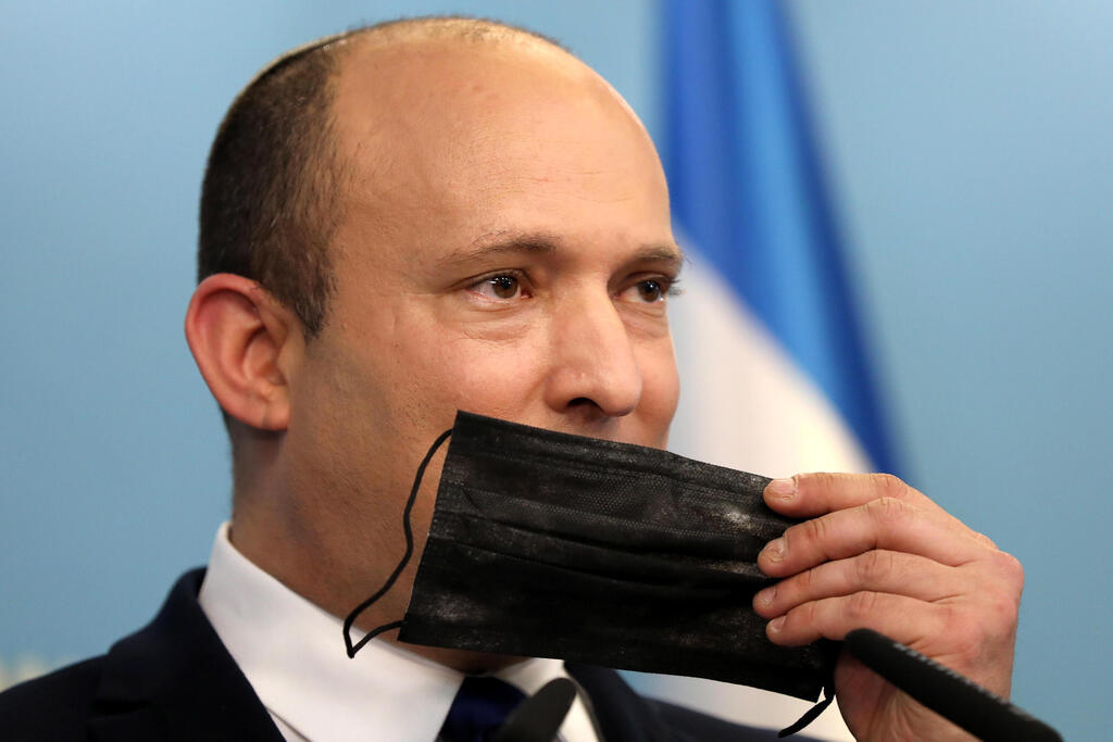 Prime Minister Naftali Bennett holds a face mask during a press conference regarding the COVID-19 situation in Israel 