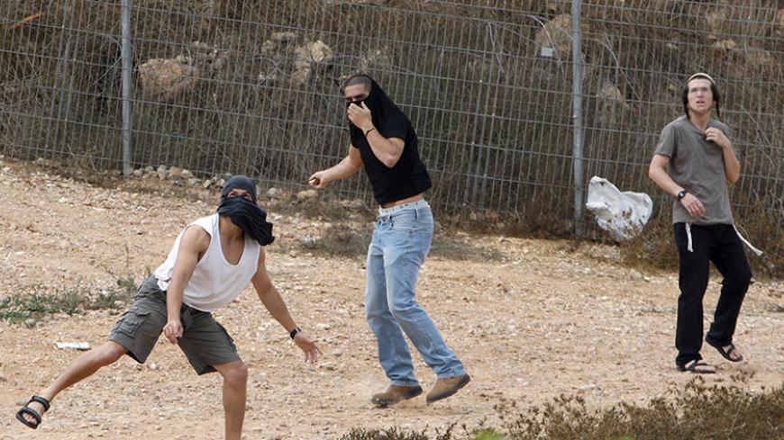 Israeli settlers throw stones at Palestinian houses (not seen) in the West Bank city of Hebron  