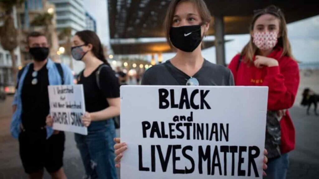 Black Lives Matter protesters hold a banner in support of Palestinians חרם BDS black lives matter