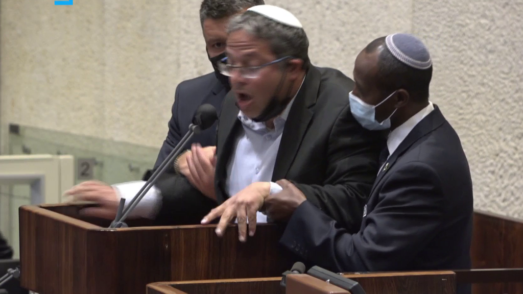 בן גביר נאחז בכוח בדוכן (צילום: ערוץ כנסת) אחמד טיבי ואיתמר בן גביר