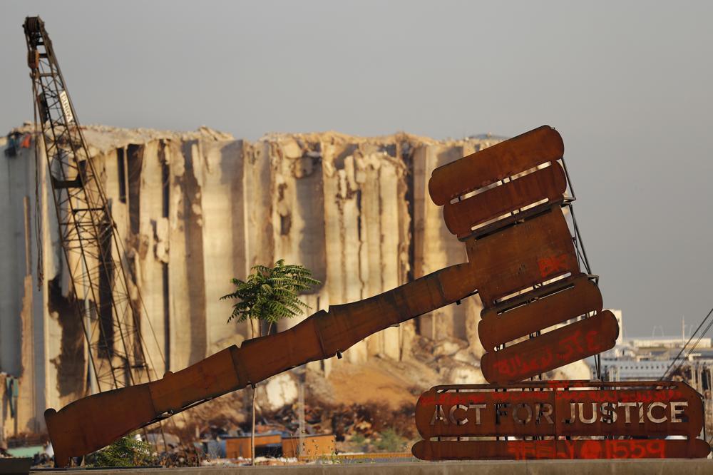 A justice symbol monument is seen in front of towering grain silos that were gutted in the massive August 2020 explosion at the port that claimed the lives of more than 200 people, in Beirut, Lebanon 