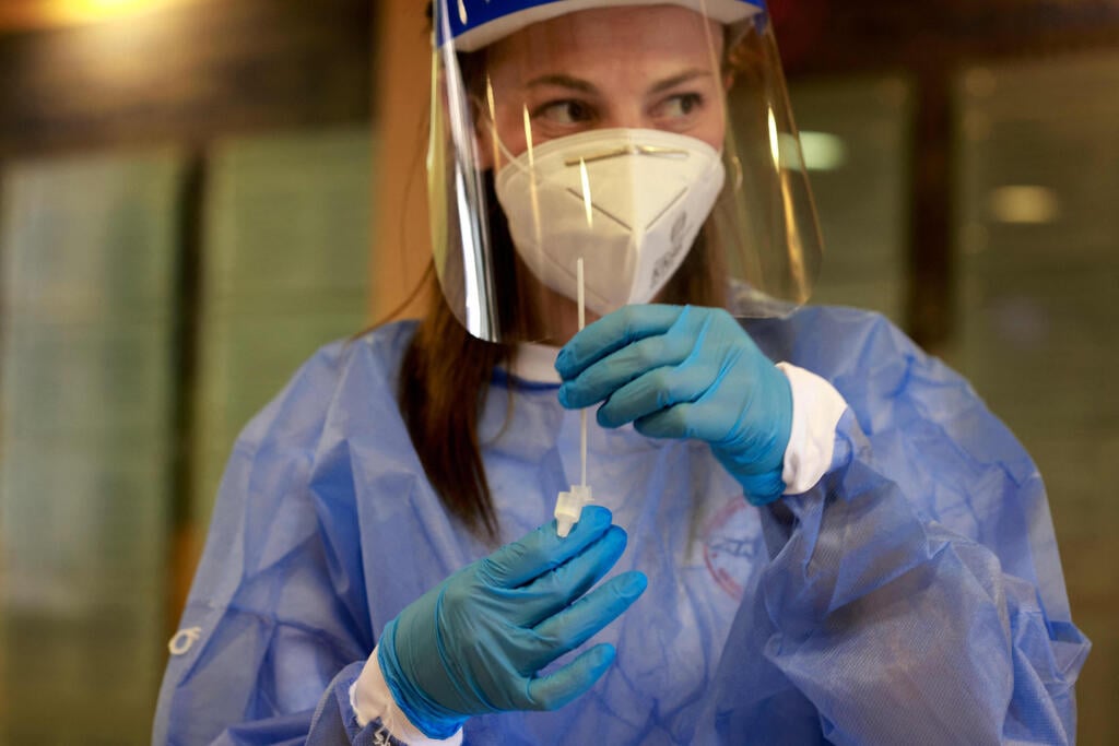 A healthcare worker holds a coronavirus test kit at a facility in Jerusalem (Photo: AFP) בדיקות קורונה מהירות בירושלים