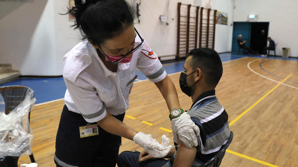 A young man receives his third dose of a coronavirus vaccine in Holon in August (Photo: AFP) חיסון שלישי של מד"א בחולון