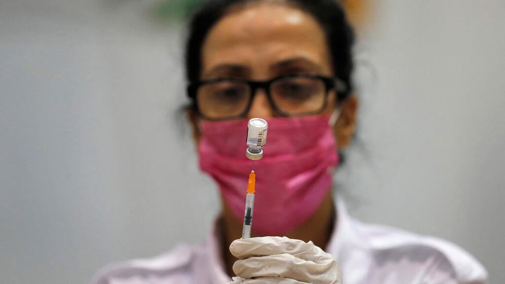 A nurse prepares to administer a coronavirus booster shot in Holon in August (Photo: AFP) חיסון שלישי של מד"א בחולון