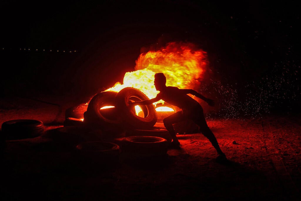Palestinian rioter burning tires along Gaza-Israel border (Photo: AFP) מתפרעים ברצועת עזה