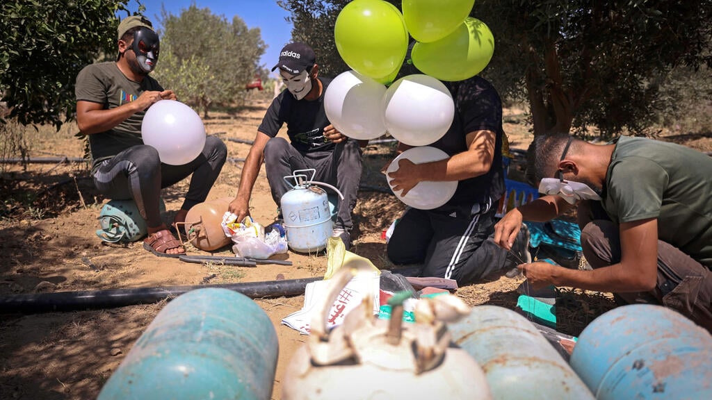 פלסטינים מפריחים בלונים עם תמונות הרוגים מהעימותים ומסרי איום