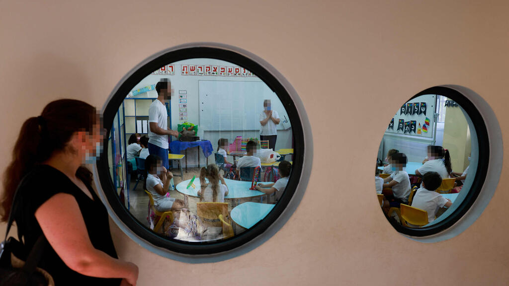 A woman looks on as first graders sit in class on the first day of school on September 1 in Jerusalem (Photo: AFP ) היום הראשון ללימודים בבית ספר בית הכרם בירושלים
