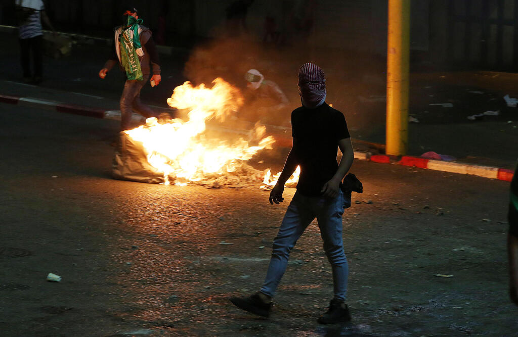 Palestinian rioters light fire as they clash with Israeli forces in West Bank city of Hebron (Photo: EPA) עימותים בחברון
