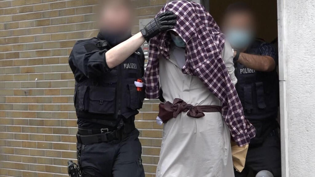 A man is taken away by police officers in connection with the suspected planned attack on the Hagen synagogue 