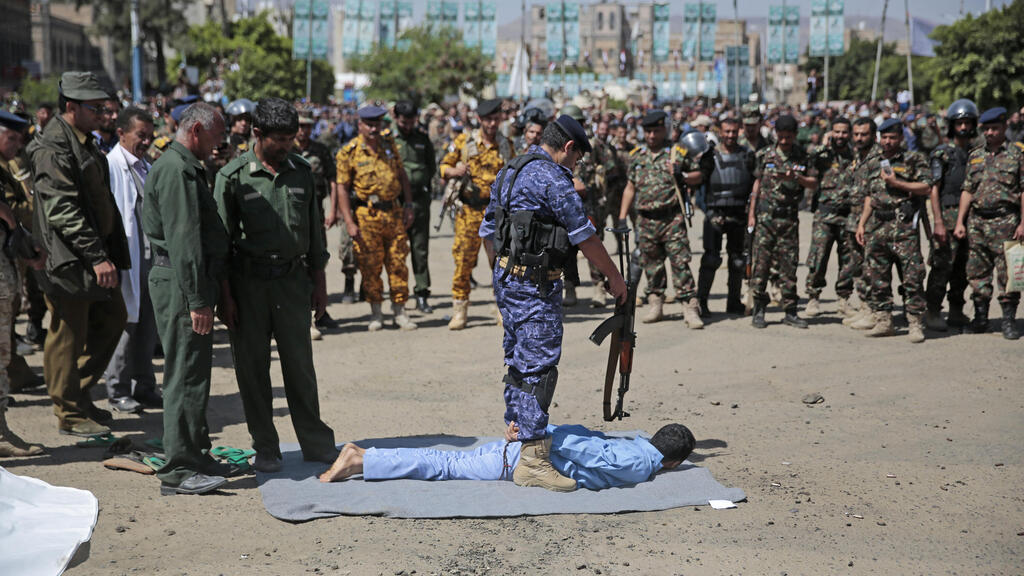 An executioner stands over a man convicted of being involved in the killing of senior Houthi official Saleh al-Samad, Saturday, Sept. 18, 2021, in Tahrir Square in Sanaa, Yemen 